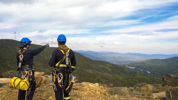 Techniciens et techniciennes face à une éolienne
