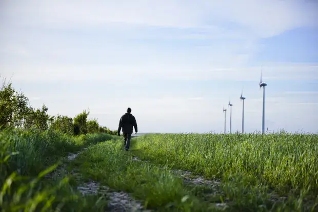 Homme marchant le long d'un chemin proche d'un parc éolien