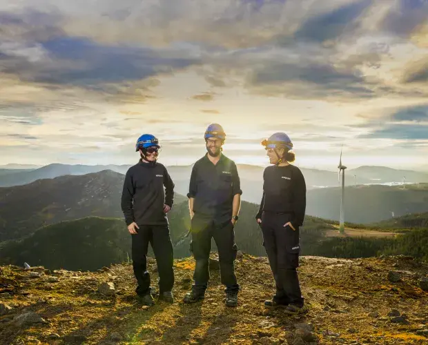 Techniciens et techniciennes face à une éolienne