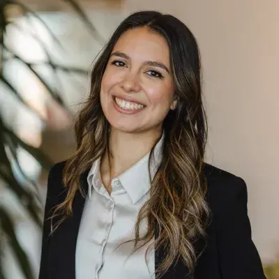 Photo de Camille Laventure souriante portant un veston noir et une chemise beige.