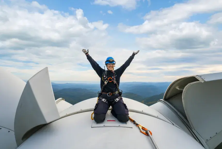 Employée sur le toit d'une éolienne levant les bras